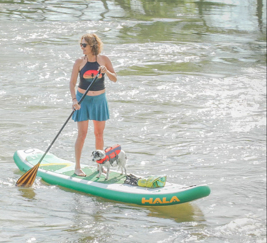 Woman paddleboarding on a lake with a dog on a board