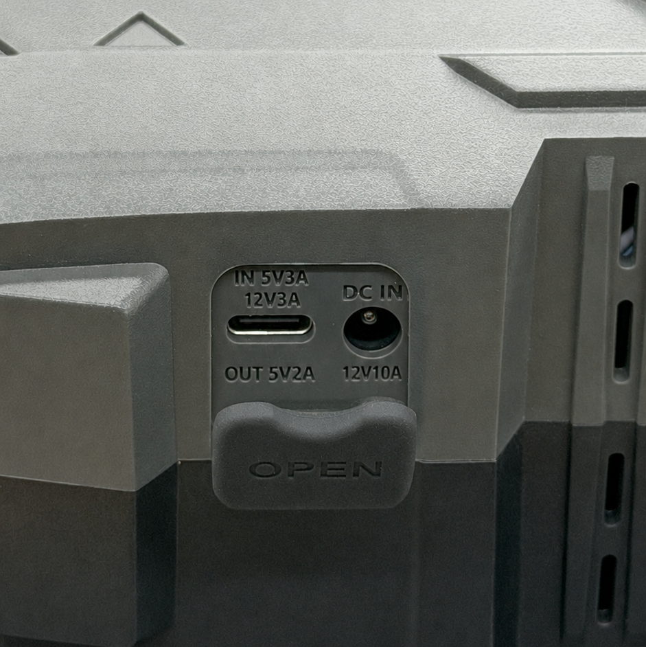 Close-up of the Hala cordless electric SUP pump port panel under its rubber cover, showing the 12V 3A charging input and 5V 2A USB-C output.